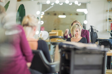 Friseurin stylt das Haar eines Kunden im Salon - ISF20149