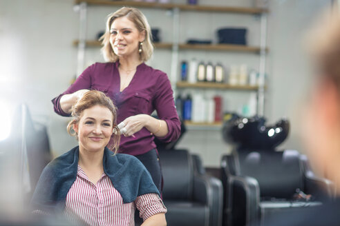 Friseurin stylt das Haar eines Kunden im Salon - ISF20150