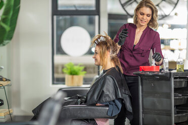 Hairdresser colouring customer's hair in salon - ISF20153