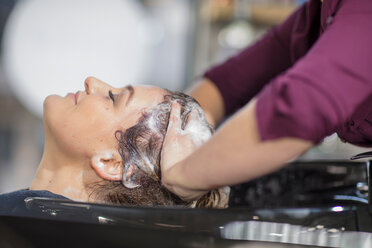 Friseurin beim Shampoonieren der Haare einer Kundin im Salon - ISF20154