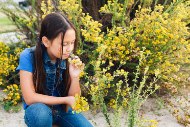 Girl kneeling to smell plant - ISF20169