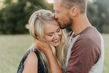 Romantischer Mann küsst Freundin auf die Stirn im Feld - ISF20174