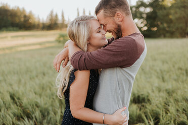 Romantischer Mann und Freundin umarmen sich in einem Feld mit langem Gras - ISF20175