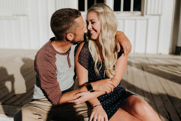 Romantic man and girlfriend sitting on porch gazing at each other - ISF20178