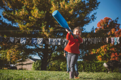 Mädchen schwingt Baseballschläger im Garten, lizenzfreies Stockfoto