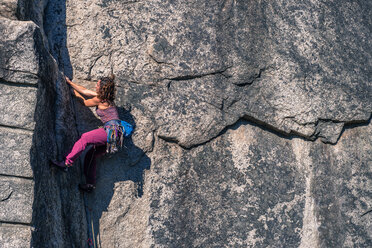 Young female rock climber climbing rock face, full length, side view, Smoke Bluffs, Squamish, British Columbia, Canada - ISF20193