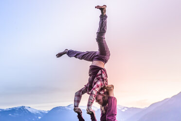 Zwei junge Frauen üben Acroyoga vor einer Bergkette bei Sonnenuntergang, Squamish, British Columbia, Kanada - ISF20194