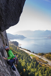 Young female rock climber climbing up rock face, elevated view, The Chief, Squamish, British Columbia, Canada - ISF20196