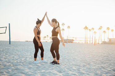 Friends hi fiving on beach, Long Beach, California, US - ISF20222