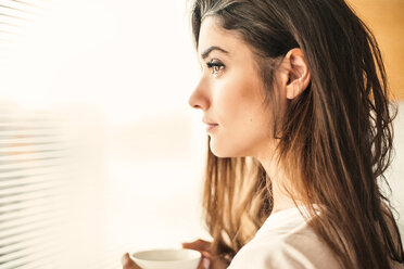 Woman with cup contemplating by window - ISF20262