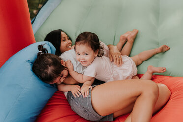 Mother and daughters playing on bouncy castle - ISF20287