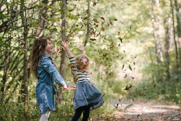 Schwestern werfen Blätter in die Luft im Wald - ISF20307