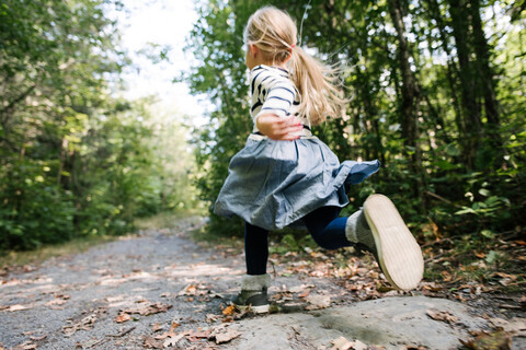 Kleines Mädchen läuft im Wald, lizenzfreies Stockfoto