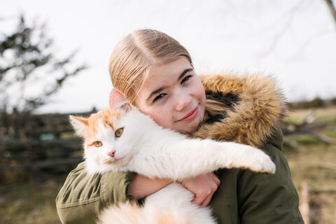 Mädchen kuschelt mit Katze im Feld, lizenzfreies Stockfoto