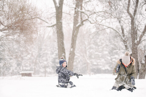 Junge wirft Schneeball auf Schwester, lizenzfreies Stockfoto