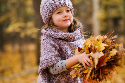 Kleines Mädchen mit einer Handvoll Herbstblätter, lizenzfreies Stockfoto