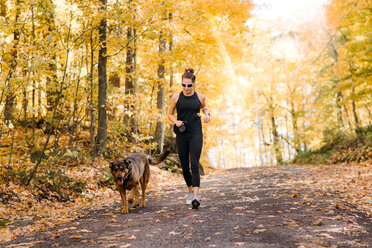 Woman jogging with dog in forest - ISF20409