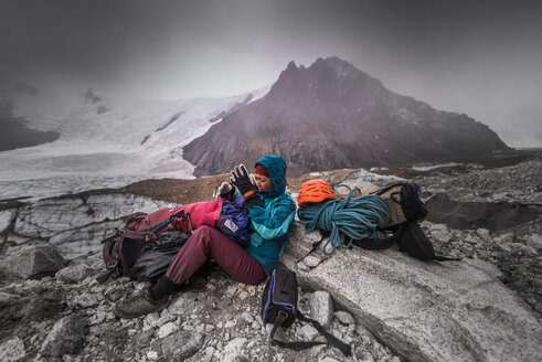 Felskletterer mit Kletterausrüstung, die vor extremen Wetterbedingungen schützt, El Chaltén, Südpatagonien, Argentinien - ISF20420