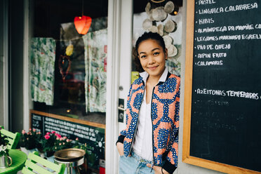 Portrait of confident young woman leaning by blackboard at restaurant - MASF10859