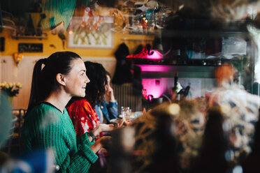 Lächelnde junge Frau gestikuliert, während sie mit multiethnischen Freunden in einem Restaurant beim Brunch sitzt - MASF10891