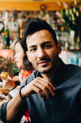 Porträt eines selbstbewussten jungen Mannes, der während einer Dinnerparty im Restaurant am Tisch sitzt - MASF10901