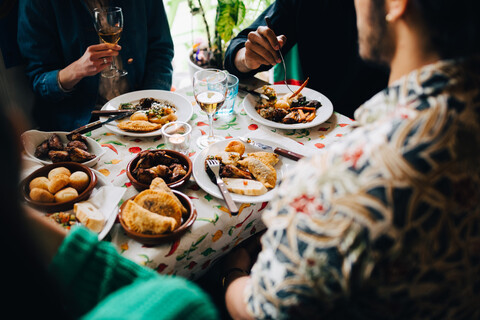 Hoher Blickwinkel auf junge multiethnische Freunde, die ihr Mittagessen genießen, während sie an einem Tisch im Restaurant sitzen, lizenzfreies Stockfoto