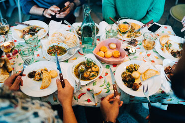 Mittelteil eines jungen multiethnischen Freundeskreises beim Mittagessen in einem Restaurant während einer Party - MASF10914