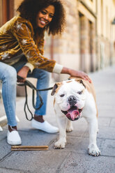 Nahaufnahme einer stehenden englischen Bulldogge mit einer sitzenden Frau im Hintergrund - MASF10921