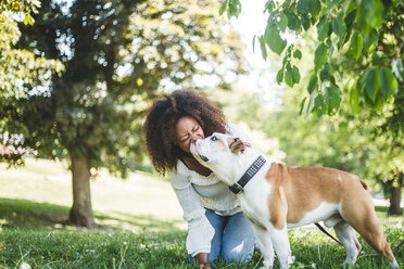 Glückliche Frau mittleren Alters mit anhänglicher Bulldogge im Park - MASF10927