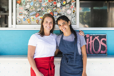 Portrait of confident young multi-ethnic female owners standing with arms around against food truck - MASF10984