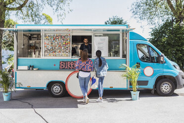 Full length rear view of female friends talking with male food truck owner in city on sunny day - MASF11005