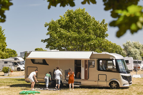 Familie gegen Wohnmobil-Camping im Wohnwagenpark während des Sommerurlaubs, lizenzfreies Stockfoto