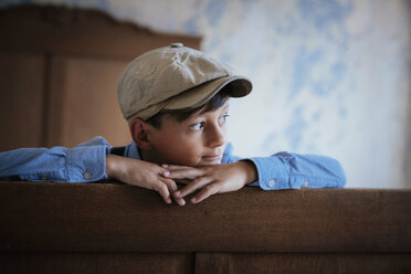 Thoughtful boy in cap looking away on bed - FSIF03736