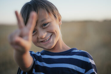 Porträt lächelnder, unbekümmerter Junge, der das Friedenszeichen macht - FSIF03740
