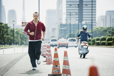 Junger Mann beim Joggen auf einer städtischen Straße, Tokio, Japan - FSIF03750