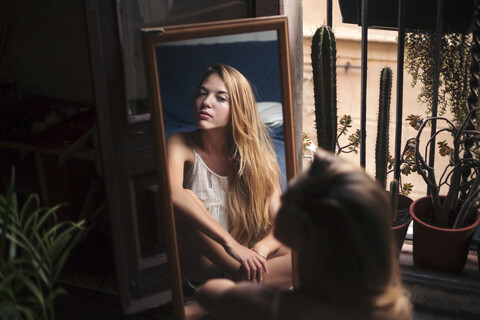 Mirror image of young woman watching herself stock photo