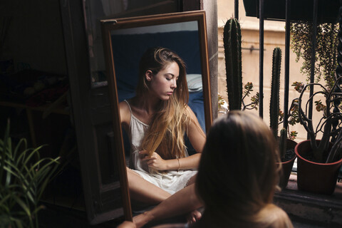 Spiegelbild einer jungen Frau, die zu Hause auf dem Boden sitzt und sich entspannt, lizenzfreies Stockfoto