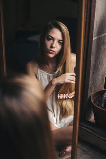 Mirror image of young woman watching herself combing - LOTF00053