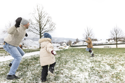 Father and two children having a snowball fight stock photo