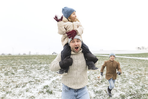 Glücklicher Vater mit zwei Kindern in Winterlandschaft - KMKF00692