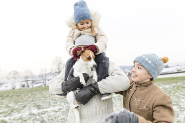 Glücklicher Vater mit zwei Kindern und Hund in Winterlandschaft - KMKF00693