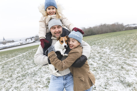 Glücklicher Vater mit zwei Kindern und Hund in Winterlandschaft, lizenzfreies Stockfoto