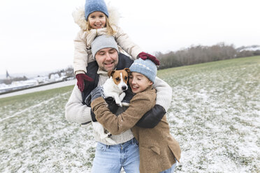 Glücklicher Vater mit zwei Kindern und Hund in Winterlandschaft - KMKF00694