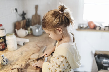 Little girl slicing bread in the kitchen - KMKF00713