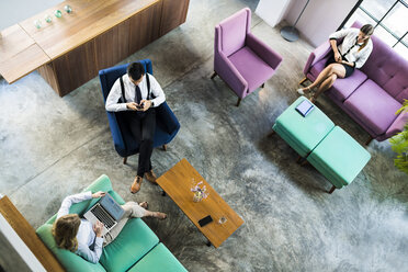 Blick von oben auf Geschäftskollegen, die mit Laptop und Smartphone in einem Coworking Space arbeiten - SBOF01547