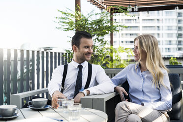 Smiling business colleagues on city terrace having a break and talking with each other - SBOF01548