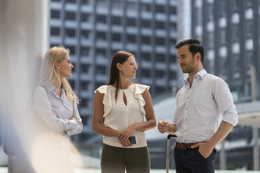 Lächelnde Geschäftskollegen im Gespräch in der Stadt vor einem Wolkenkratzer - SBOF01557