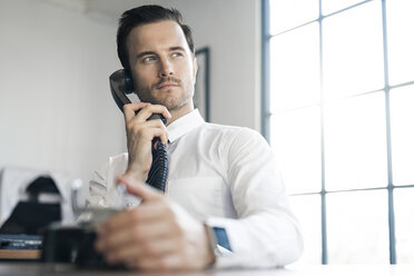 Businessman in office using vintage retro telephone - SBOF01571