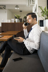 Geschäftsmann genießt Kaffee und macht eine Pause auf einer Bank in einem Cafe - SBOF01602