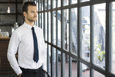 Confident businessman looking out of window - SBOF01608